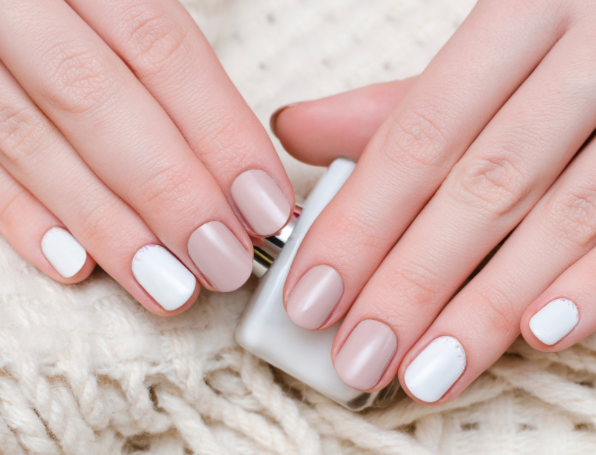 Manicured female hands holding a bottle of nail polish