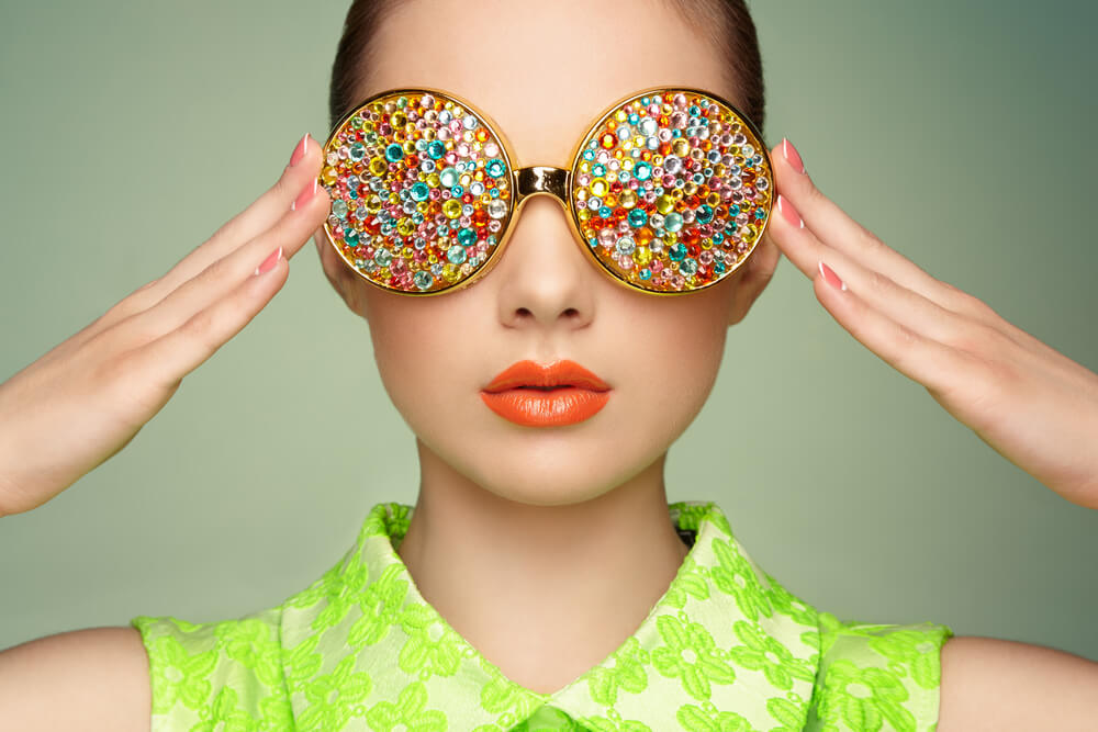 Young woman wearing a green shirt with large multicoloured sunglasses